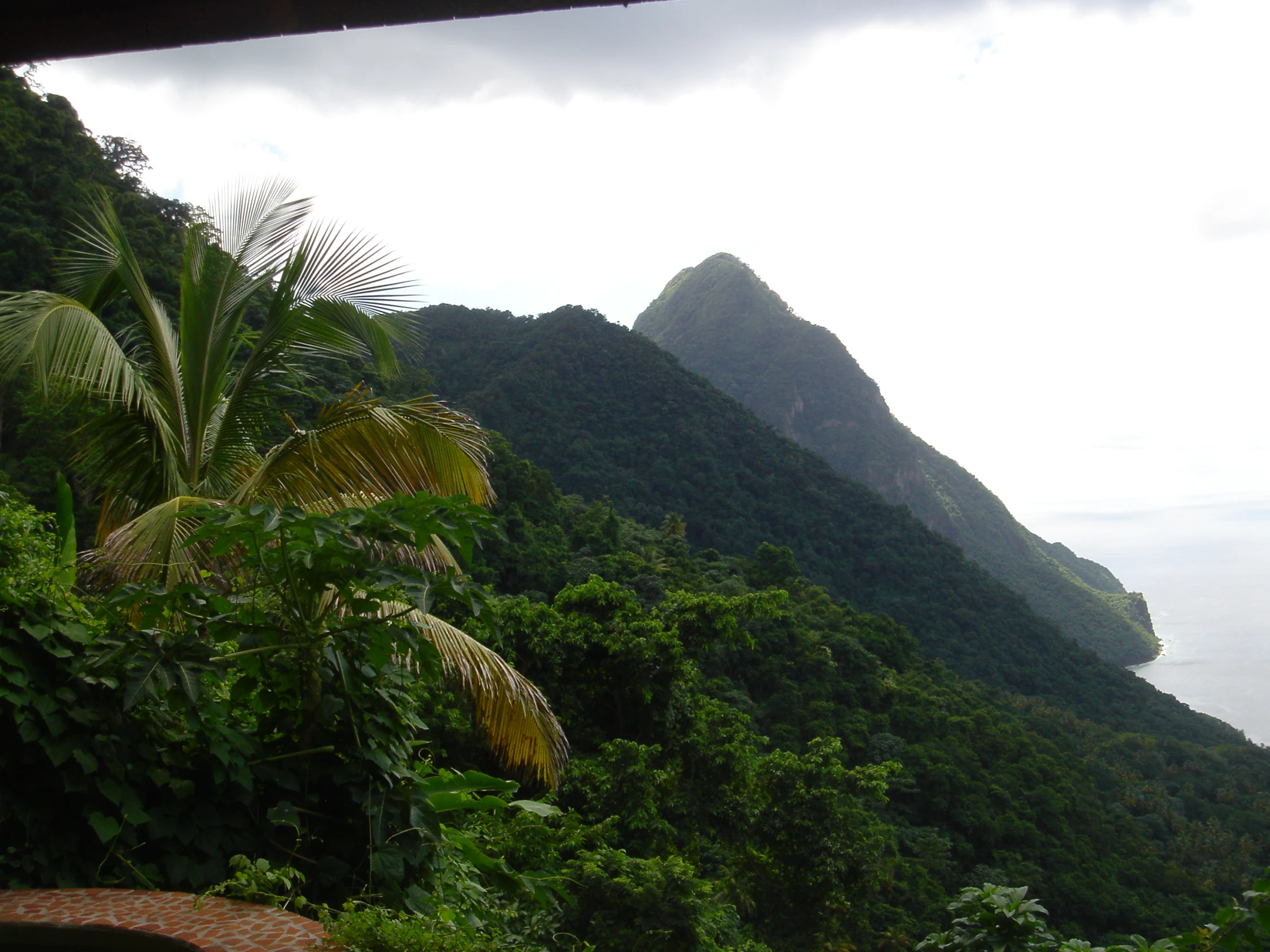 the view of mountains, greenery, and trees are shown from a balcony