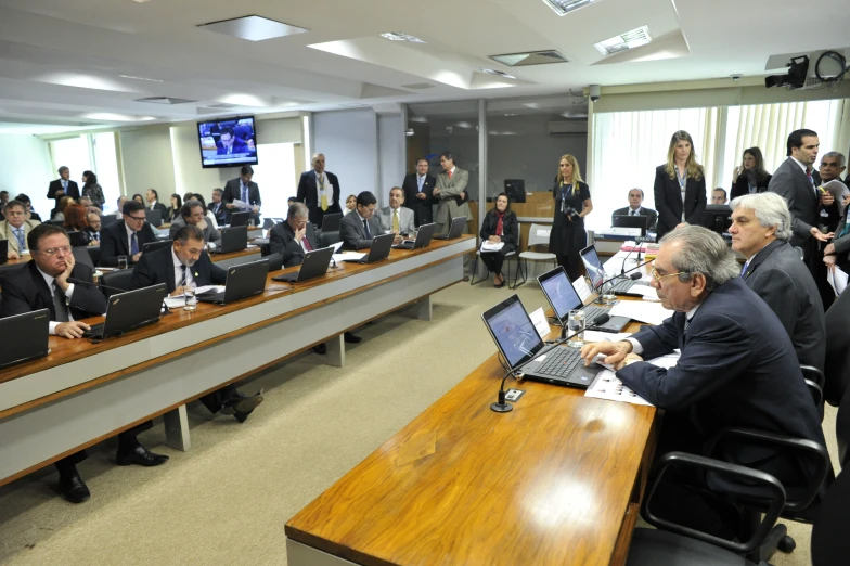 many people in suits sitting at a long wooden table