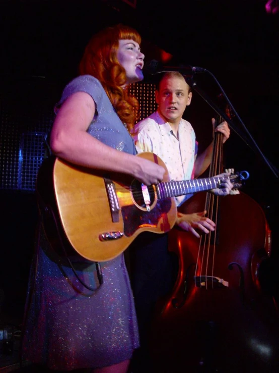 a man playing a guitar next to another person on a stage