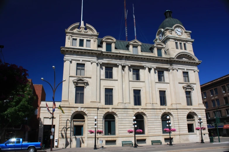 a tan brick building with clocks on it on the corner