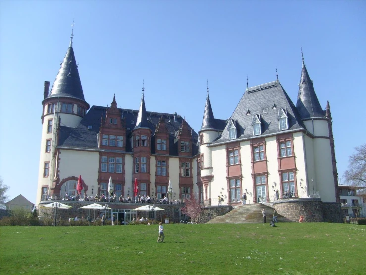 a large building with towers in front of a grassy field