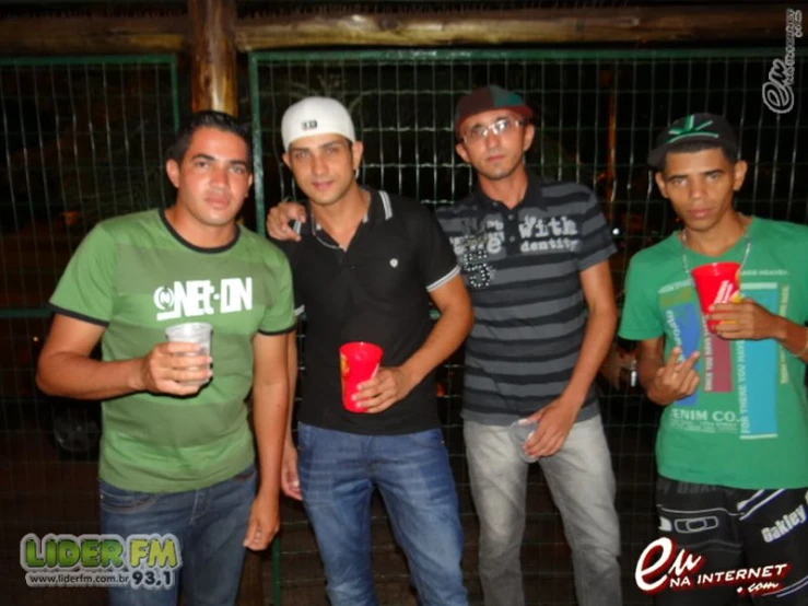 four men pose together, one holding a plastic cup