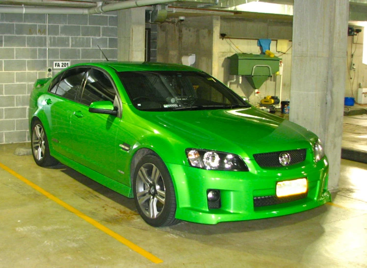 a green sports car is in an underground parking lot