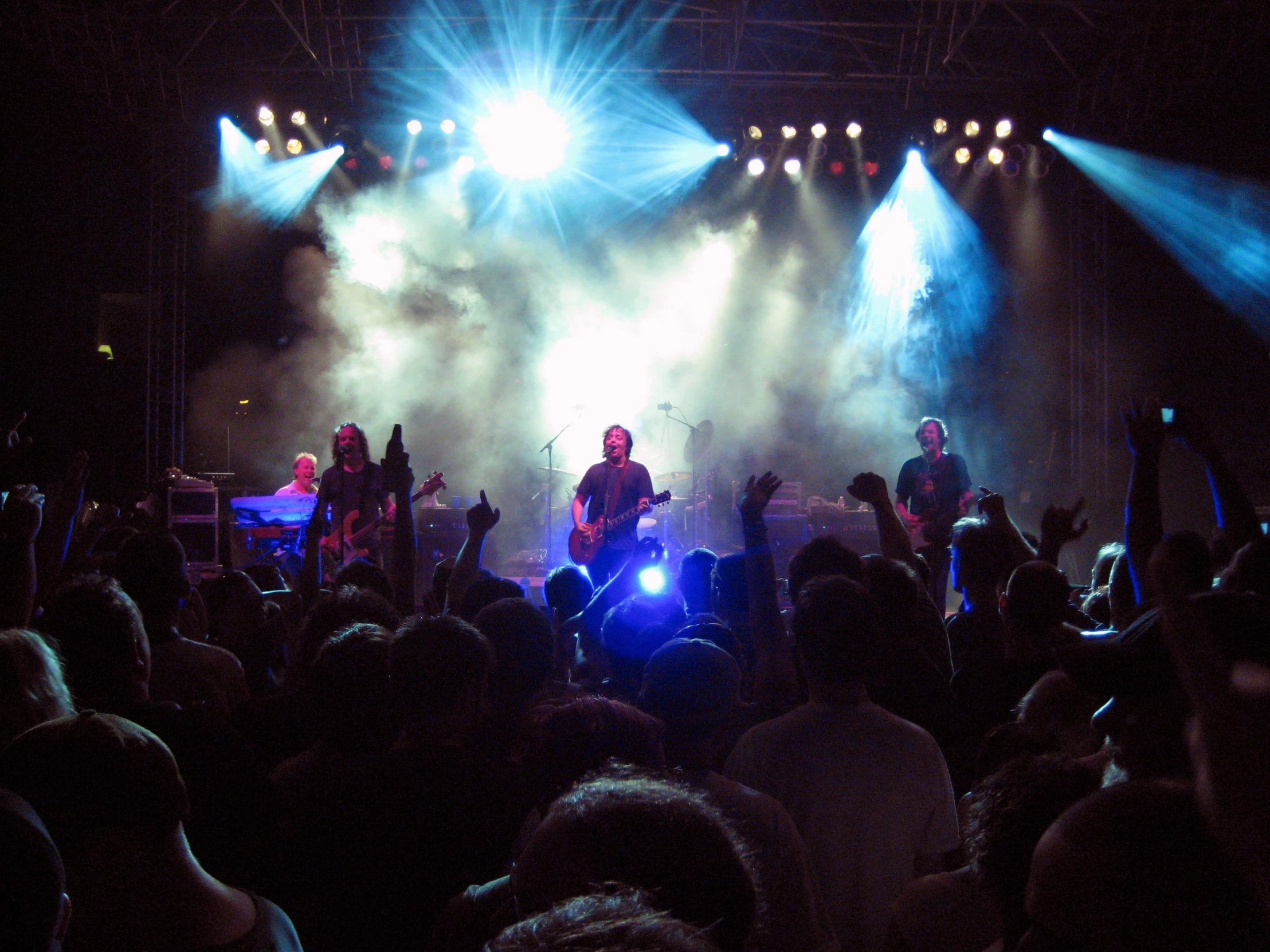 two men are playing music on stage surrounded by many people