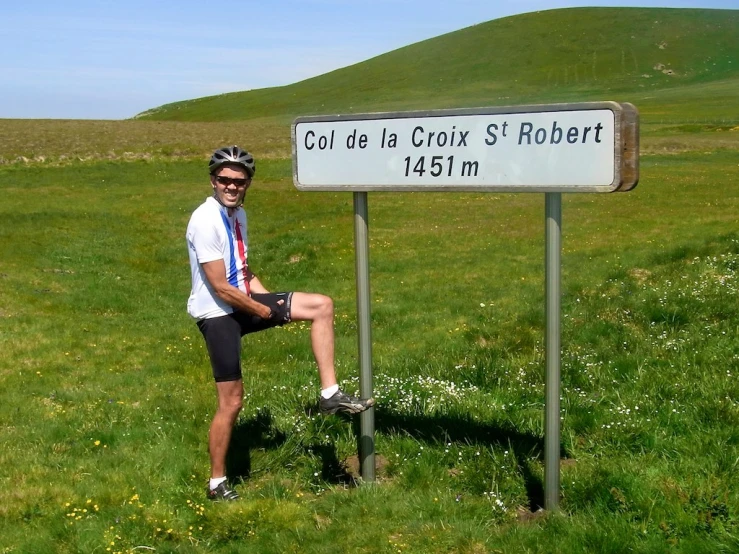 the cyclist is sitting by the sign on the grass