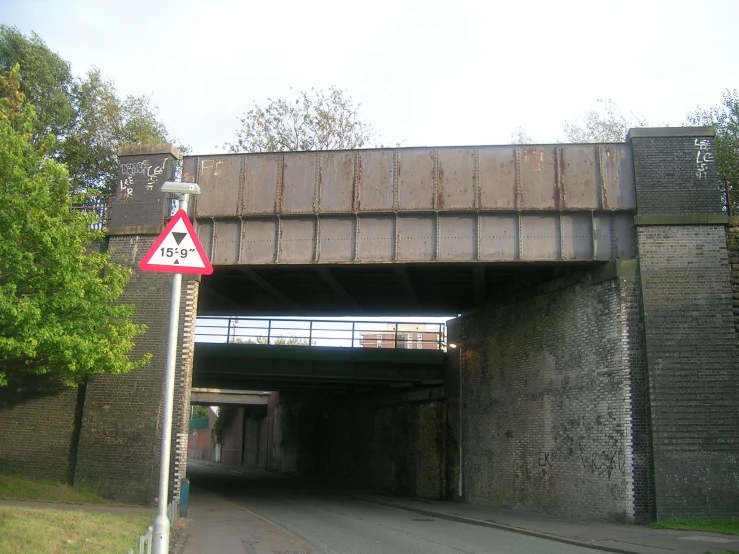 a red traffic sign sitting underneath an overpass