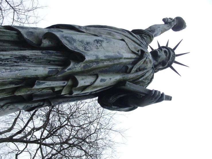 a statue is near tree nches and the sky