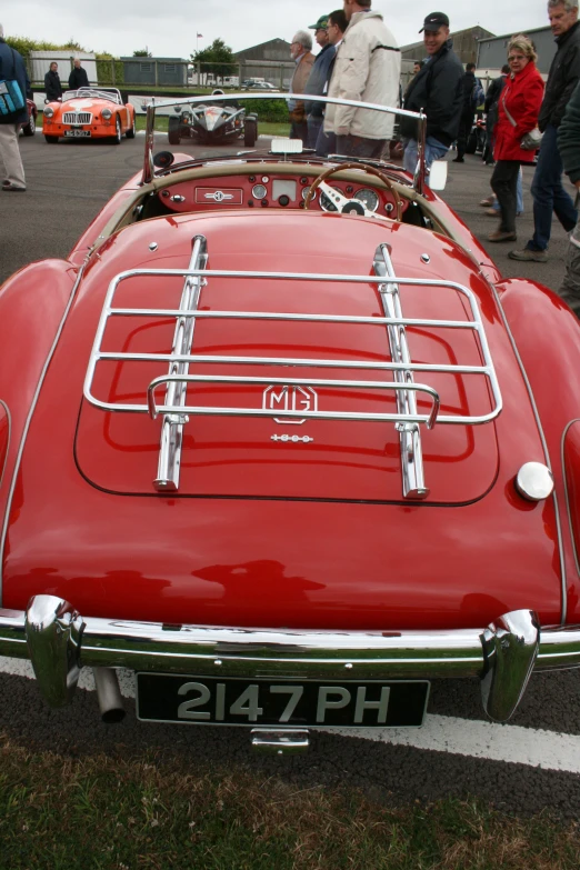 a red vintage car is parked in a lot