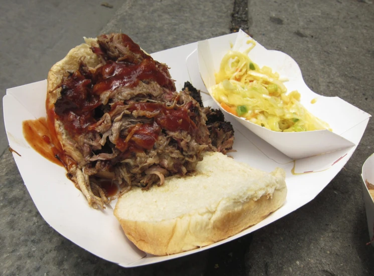 a plate with a meaty sandwich, a side dish and condiments