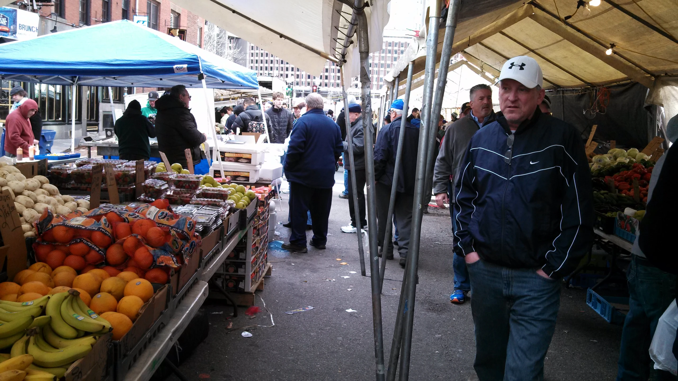 some people at a farmer's market and some are selling fruits