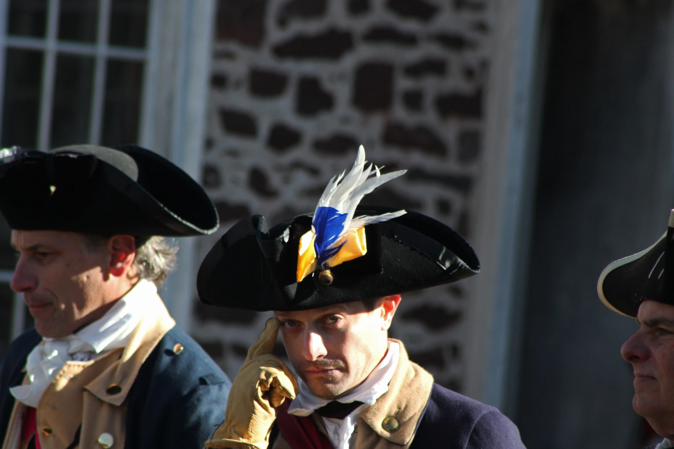 men in historical costume looking toward soing while talking on the phone