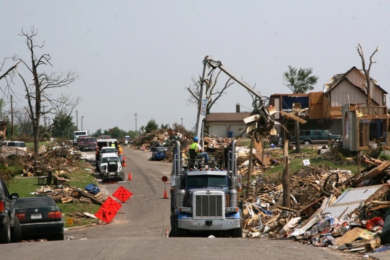 a truck is parked on a street near a pile of wood and debris