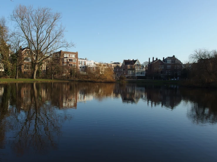 several houses are reflected in a calm river