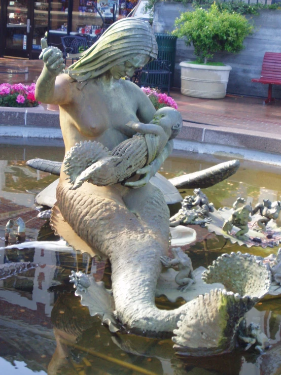 a sculpture of a mermaid riding a large elephant in a park