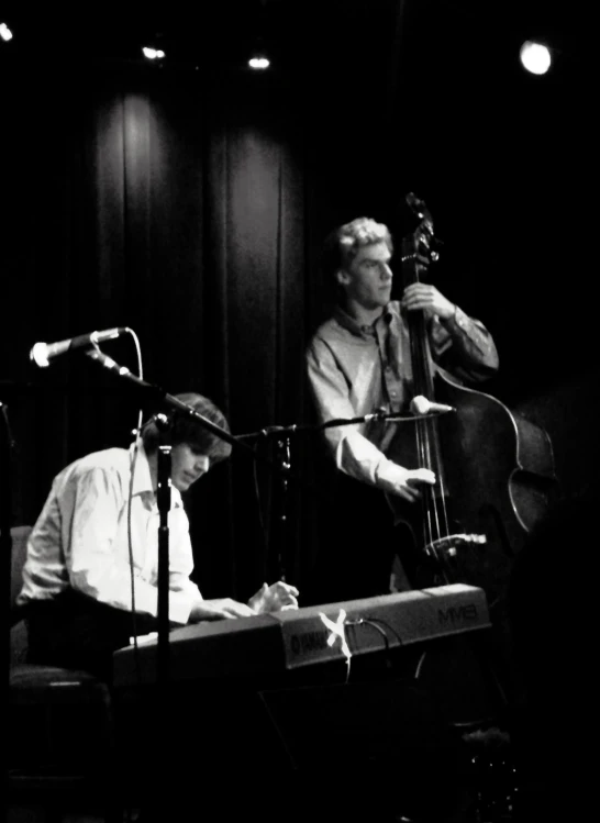 two people in front of a microphone and keyboard with their instruments