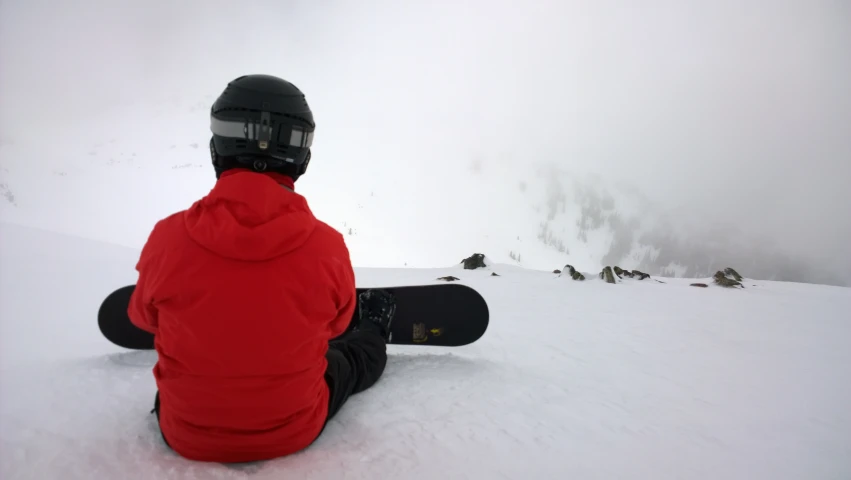 snowboarder sitting in the snow on a cloudy day