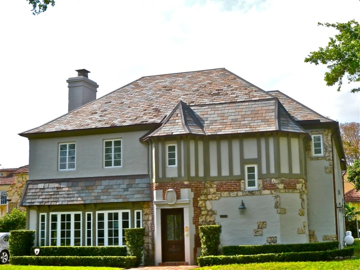 a house in the daytime with bushes and lawn