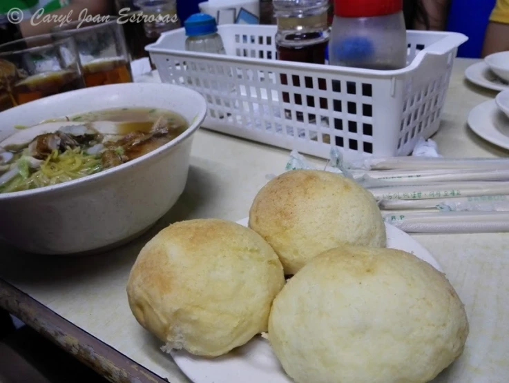 three rolls and bowl of soup sitting on a counter