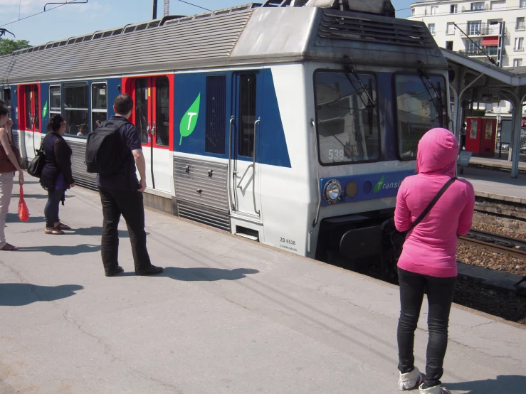 several people are waiting for the subway to stop