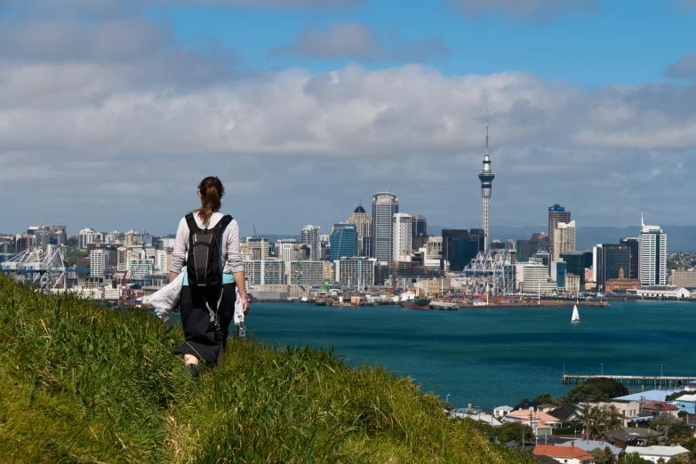 a woman walking down a hill overlooking a city