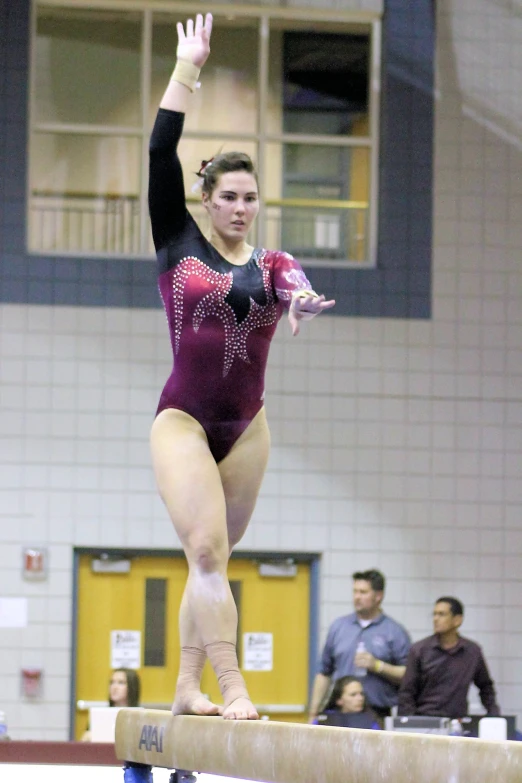 young female athlete balances on a balance beam during an event