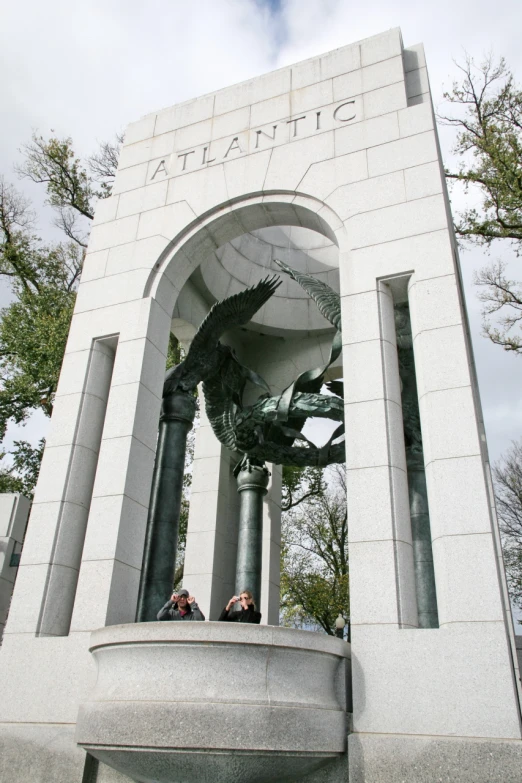 two people standing in front of a very tall statue