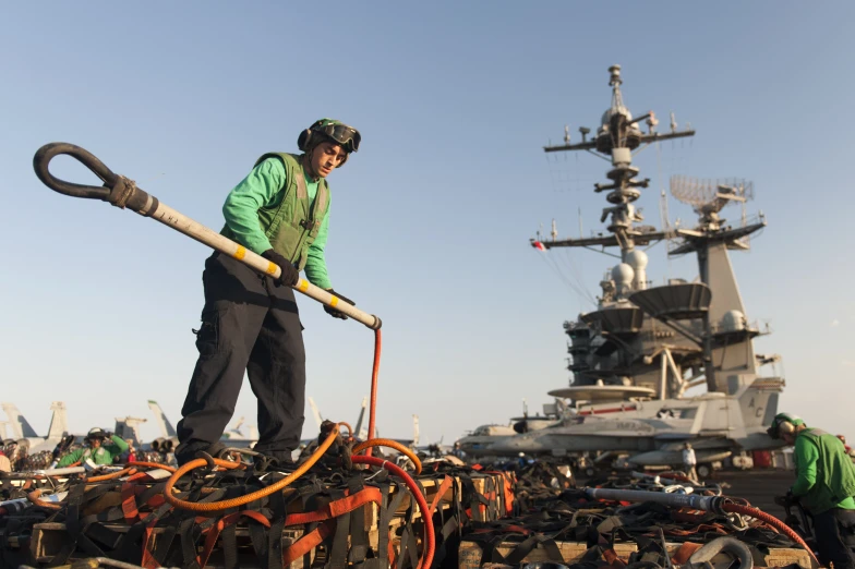 a man with a shovel stands on a raft in front of a battleship