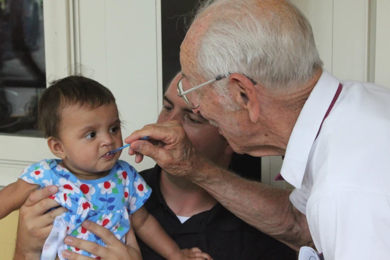 a man holds his child while another man brushes his teeth