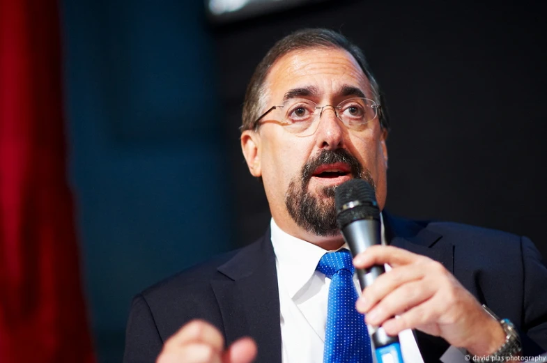 a man wearing a suit and tie holding a microphone