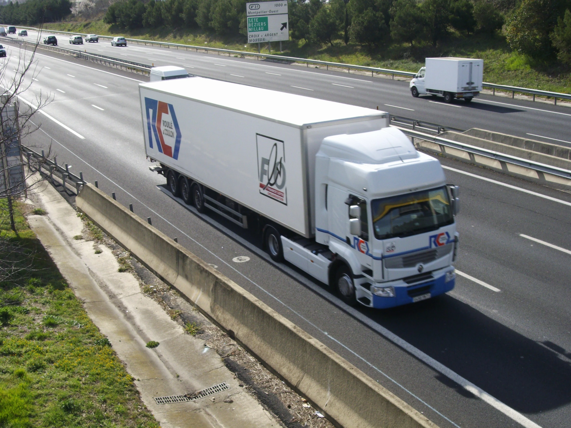 a semi truck traveling down a highway next to other cars