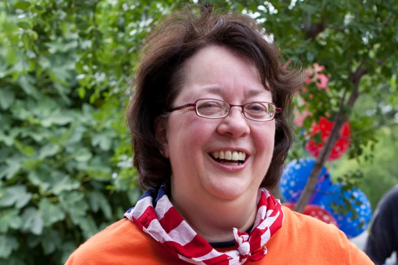 a woman wearing an orange sweater and a red and white scarf