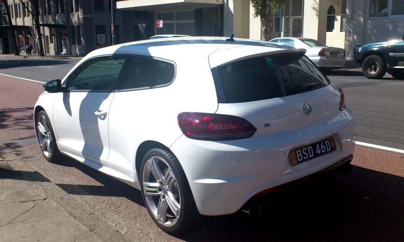 the back end of a white car parked on the street