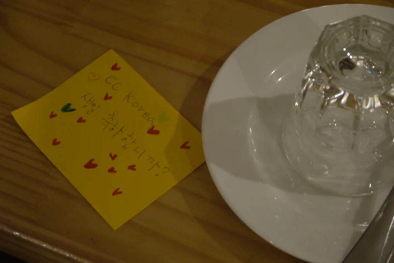 there is a note and a wine glass on the table