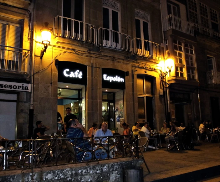 many people sitting at tables in front of a cafe
