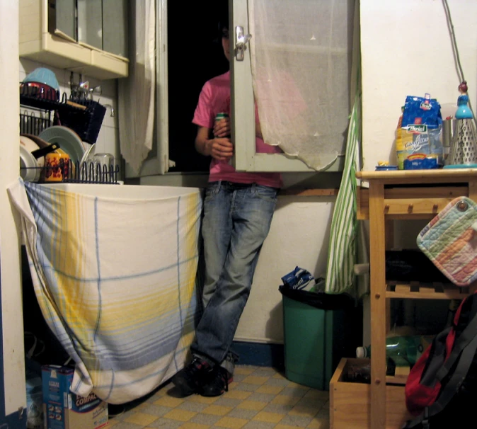 a man is standing in the kitchen holding his hand up to the door