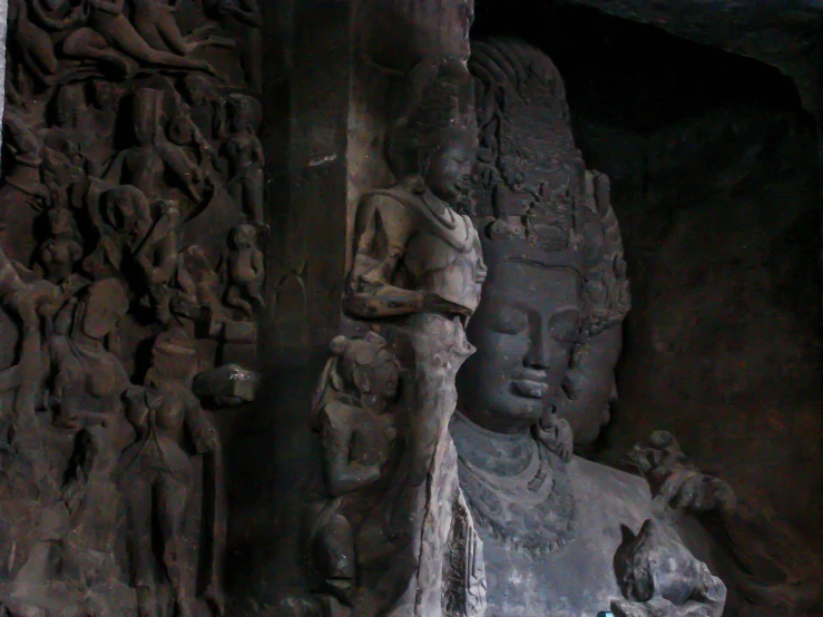 statues displayed near large stone carvings at outdoor area