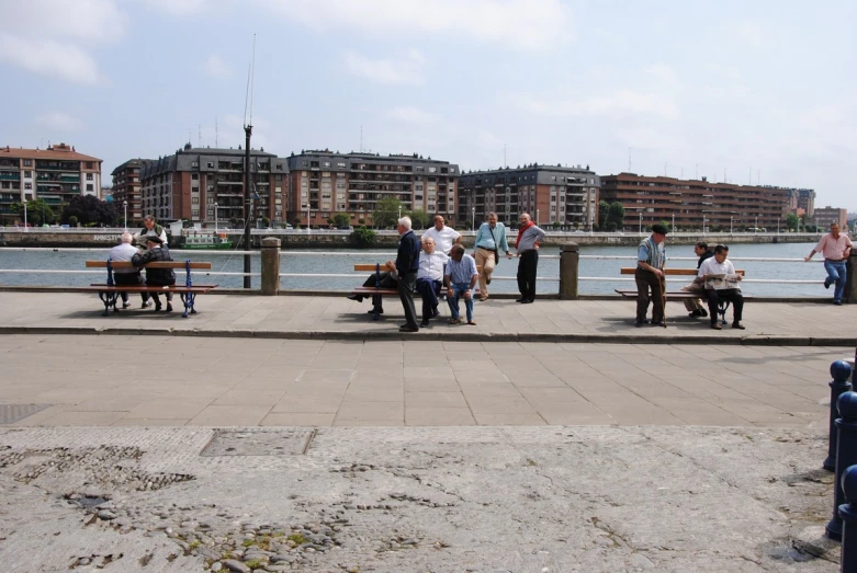 a group of people sitting on benches by a river