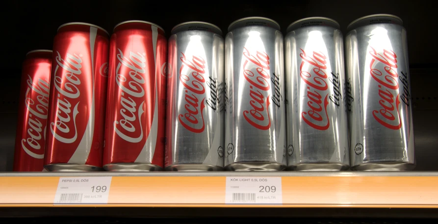 six cans of soda are sitting on a shelf