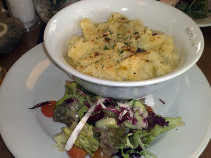 a bowl filled with food next to some salad