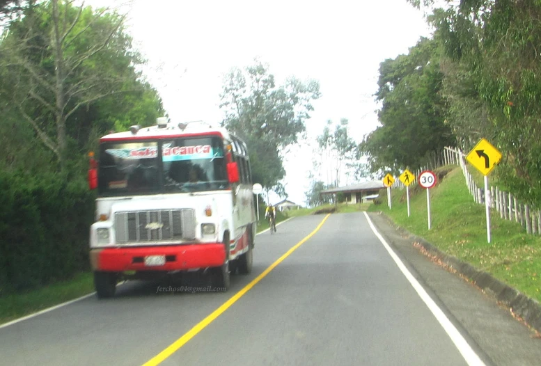 a small red and white bus traveling down a road
