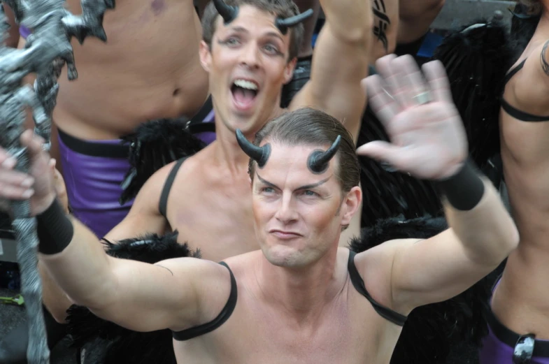 men in devil costumes with horns performing for the camera