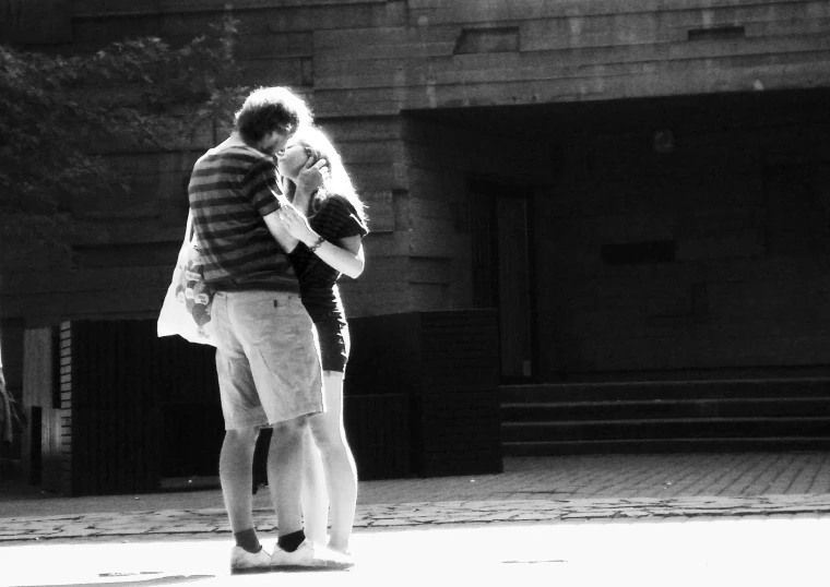 two people holding hands while standing on a sidewalk