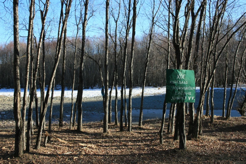 a sign next to trees and snow on a path