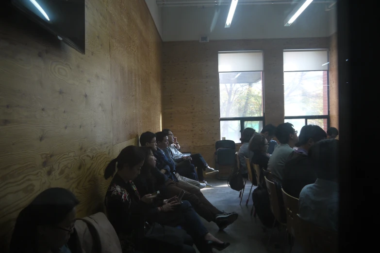 a group of people sitting in a building next to tall windows