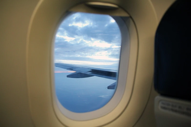 the view out of an airplane window of a wing and a plane's wing, with the ocean outside