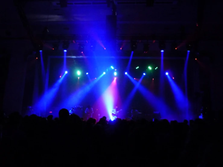 purple and blue lights shine through a stage as the crowd looks on