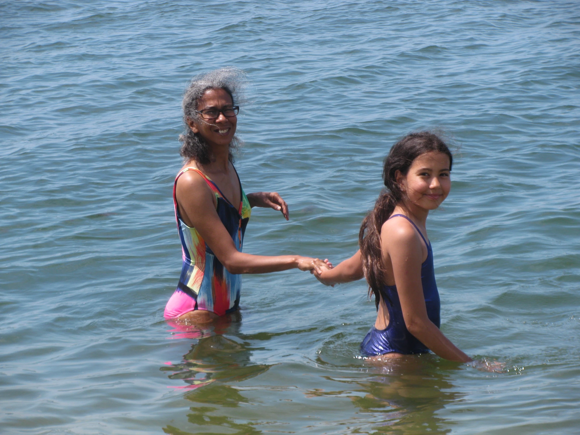 two girls in the water holding hands and smiling