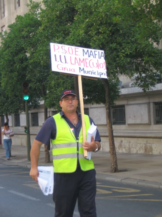 a man in safety vest standing under a traffic sign