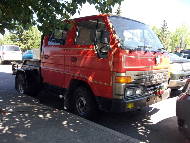 a red van parked in front of a tree on the side of a street