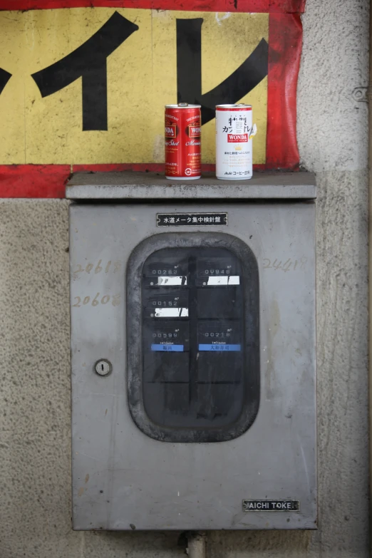 a machine and three cans that are sitting on a wall